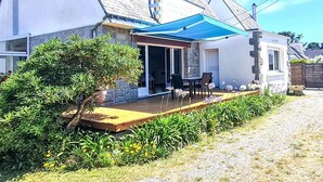 A house with a covered patio, a stone exterior, and a small garden.