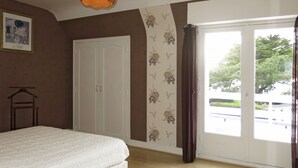 A bedroom with a bed, wardrobe, and a view through a door.