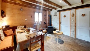 A cozy cabin interior with a wooden dining table, chairs, a fireplace, and stone walls. - Lovely home in Le Ménil (Le Ménil)