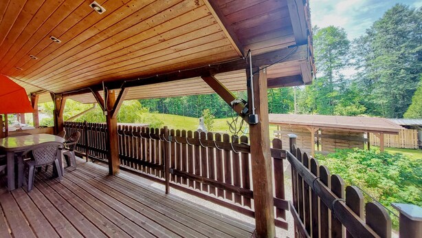 A wooden deck with a table and chairs, surrounded by a wooden fence, overlooking a grassy area with trees. - Lovely home in Le Ménil (Le Ménil)