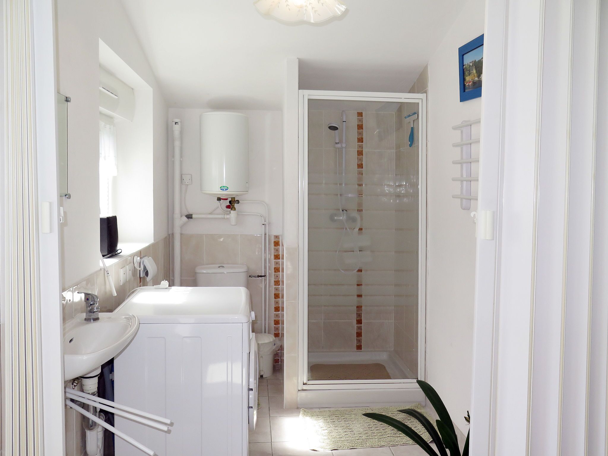 A narrow bathroom with a toilet, sink, and shower.