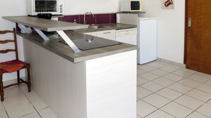 Una cucina compatta con forno a microonde integrato, un piccolo frigorifero e un lavandino.