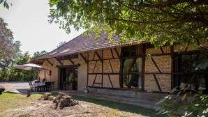 A traditional half-timbered building with a brick facade, a tiled roof, and a covered patio area with outdoor seating. - Alexandre by Interhome (La Chapelle-Saint-Sauveur)