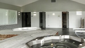 A modern spa area with a large hot tub, a wooden deck, and a seating area with lounge chairs. - Le Village de la Mer by Interhome (Talmont Saint Hilaire)