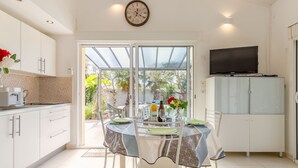 A modern kitchen with a dining area, a TV, and a view of the outdoors. - Les Oliviers by Interhome (Talmont Saint Hilaire)