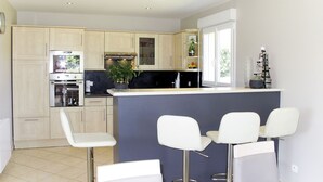 Una cocina moderna con una isla central, taburetes de bar y horno empotrado.