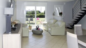 Amplia sala de estar con diseño moderno, que incluye un sofá, sillones, una mesa de centro y una escalera.