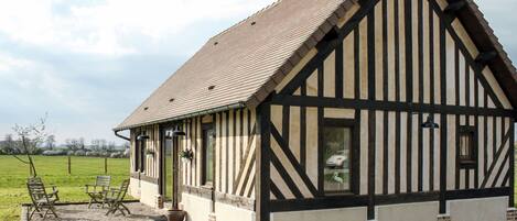 A traditional half-timbered building with a sloped roof, a gravel driveway, and outdoor seating.