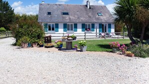 Een twee verdiepingen tellend huis met een grindpad, plantenbakken en een houten hek.