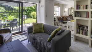 Una sala moderna con un sofá, una estantería y un comedor con sillas y una mesa.