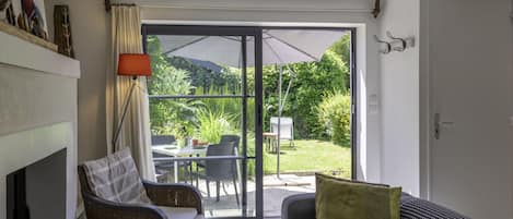 A cozy living room with a fireplace, a sofa, and a dining area with outdoor seating.
