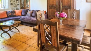 A cozy living room with a sofa, wooden dining table, and chairs. - La Bonneraie by Interhome (St.Maurice-en-Cotentin)