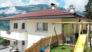 A house with a balcony, a wooden fence, a slide, and a view of mountains. - Apartment Huber by Interhome (Zell am Ziller)