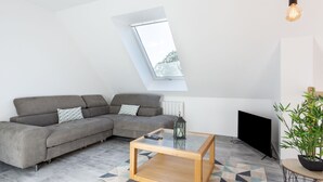 A modern living room with a sectional sofa, a glass-top coffee table, a fireplace, and a skylight.