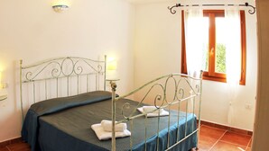 A single bed with a metal frame, a blue bedspread, and two white towels.