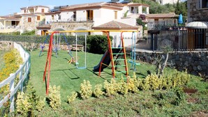 A residential area with a playground, stone buildings, and a clear sky.
