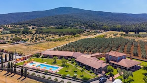 A hotel with a swimming pool, multiple buildings, and a mountainous backdrop.