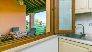 A kitchen with a window view of a patio area, a sink, and a table set for dining.