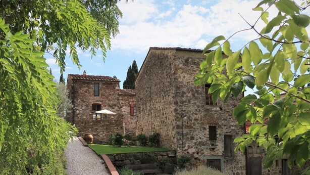 Un bâtiment en pierre avec un chemin de gravier menant à une pelouse verdoyante.