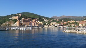 A coastal town with a marina, buildings with red and yellow facades, and hills in the background. - Baroccia da Mary by Interhome (Rio Marina)