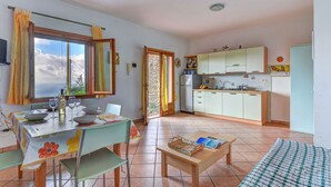 A compact kitchen with a dining area, a small table with chairs, and a view through a window. - Apartment Giulia by Interhome (Capoliveri)
