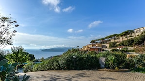 A coastal view with buildings on a hillside, a clear sky, and a body of water in the distance. - Apartment Giulia by Interhome (Capoliveri)