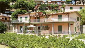A hillside residential area with terraced houses, balconies, and a vineyard in the foreground. - Apartment Giulia by Interhome (Capoliveri)