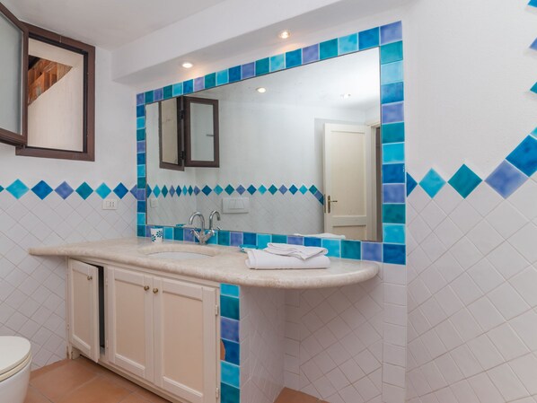 A bathroom with a white sink, a mirror, and blue-tiled walls. - Vacation home Mimosa by Interhome (Palau)