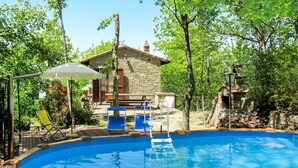 Una piscina con sillones de descanso y un edificio de piedra al fondo.
