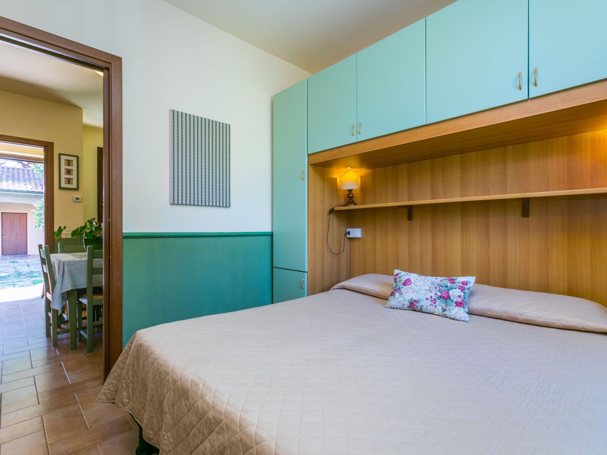 Une chambre à coucher avec un lit, une table de chevet, une lampe et une fenêtre.