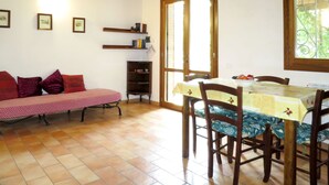 Un coin repas accueillant avec une table et des chaises en bois, un banc avec des coussins et une bibliothèque.