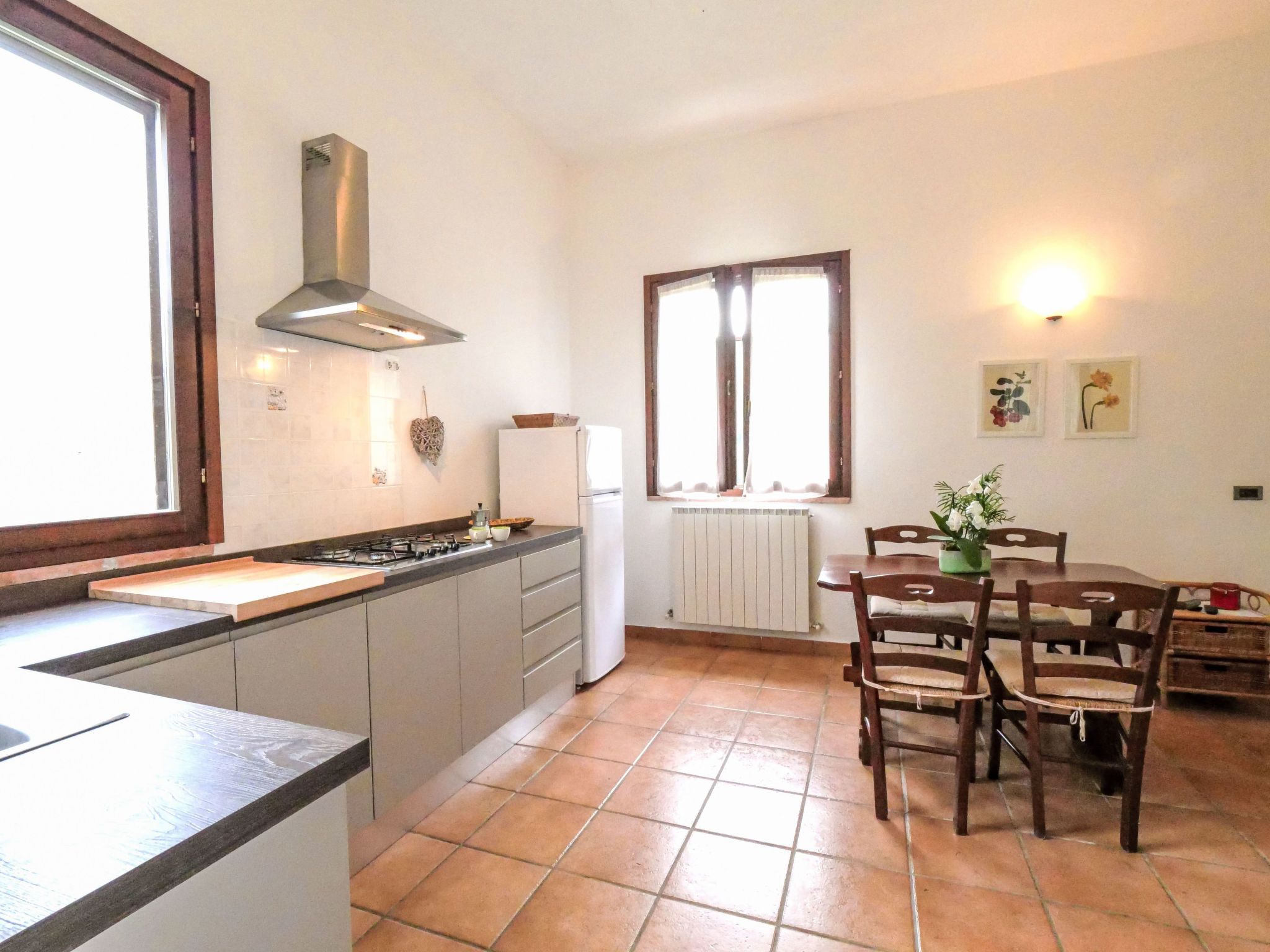 A compact kitchen with a gas stove, white cabinets, and a window above the sink.