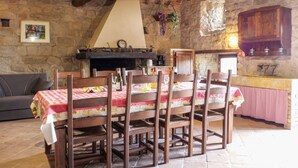 A rustic dining area with a stone wall, wooden furniture, and a fireplace.