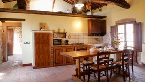 Une cuisine rustique avec des poutres en bois, un dosseret carrelé et un mur en pierre.