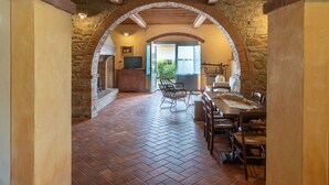 An arched stone corridor leading to a dining area with a brick floor and rustic wooden beams. - Santa Lucia by Interhome (Castiglion Fiorentino)