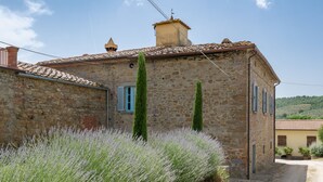 A stone building with a tiled roof, a narrow entrance, and a garden with lavender plants. - Santa Lucia by Interhome (Castiglion Fiorentino)