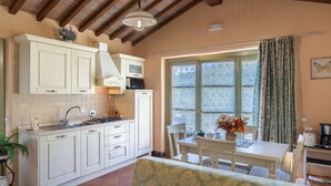 Una cocina con armarios blancos, una mesa de comedor y una ventana con cortinas.