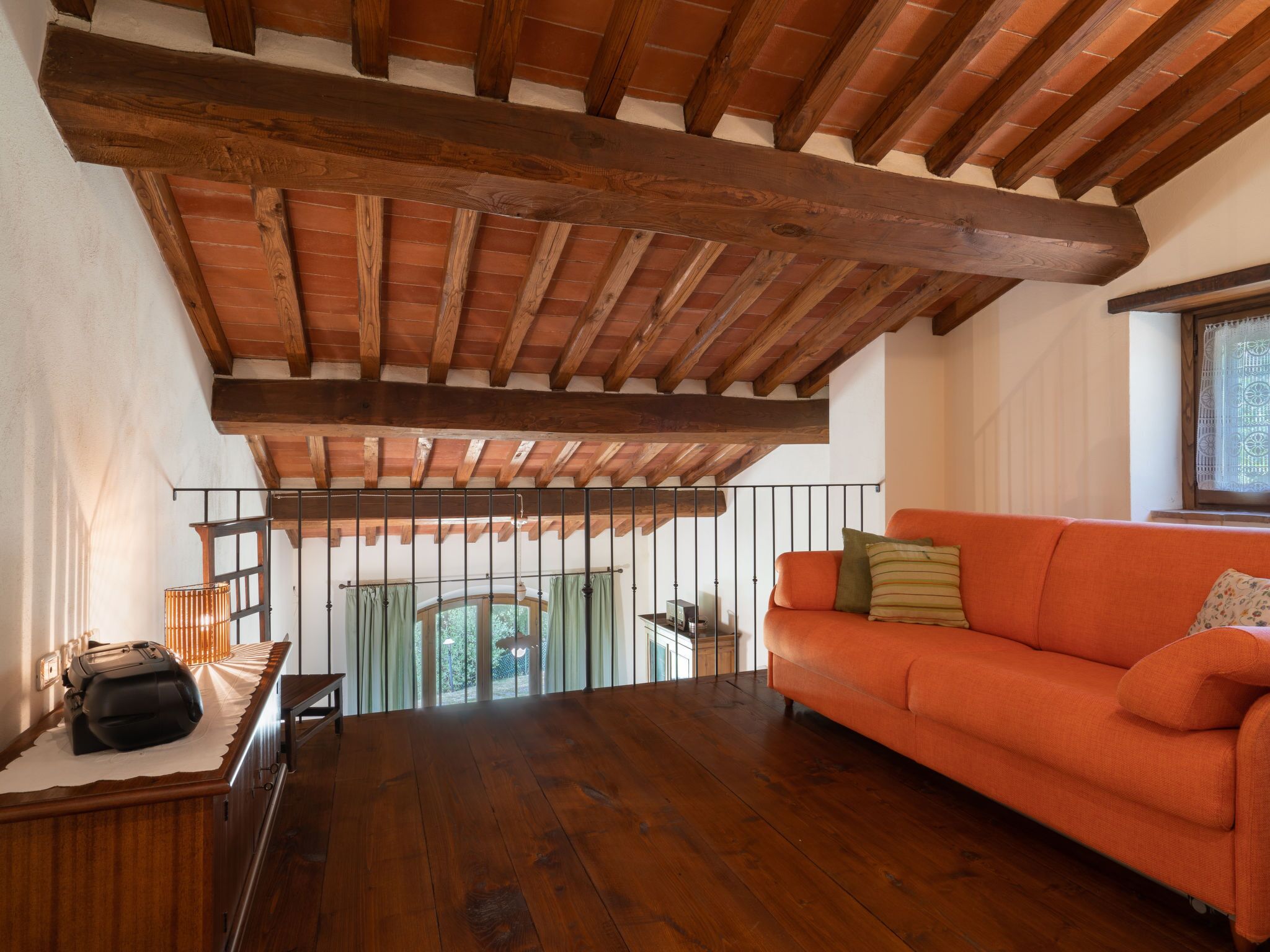 Ein geräumiges Zimmer mit Holzbalkendecke, einem Sofa und einem Tisch.