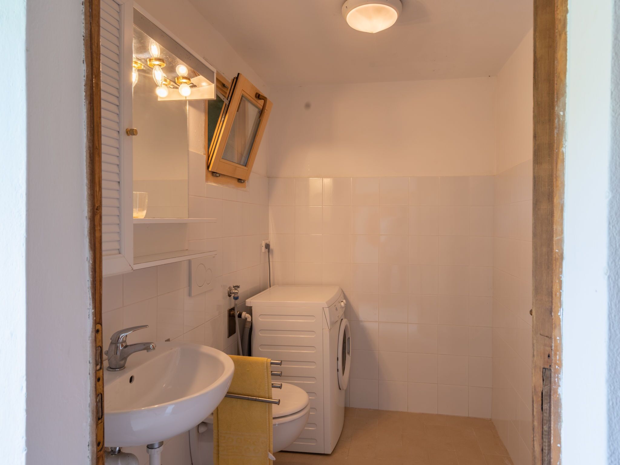 Ein kleines, sauberes Badezimmer mit Waschbecken, Spiegel und Toilette.