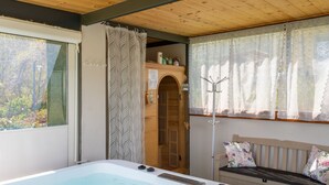 Een kamer met een groot bad, een houten plafond en een raam met gordijn.