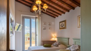 Een slaapkamer met twee bedden, een kroonluchter, een balkon met uitzicht en een deur naar buiten.