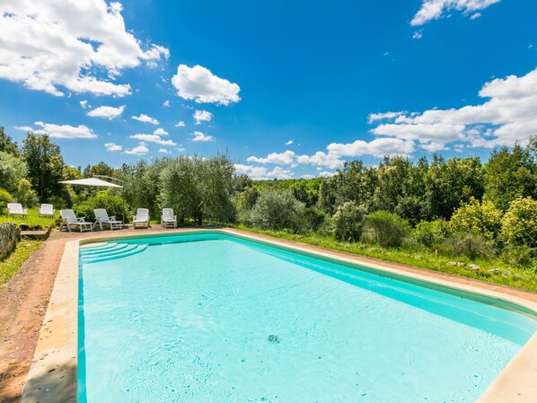 A rectangular swimming pool with a clear blue water surface, surrounded by a brick patio.