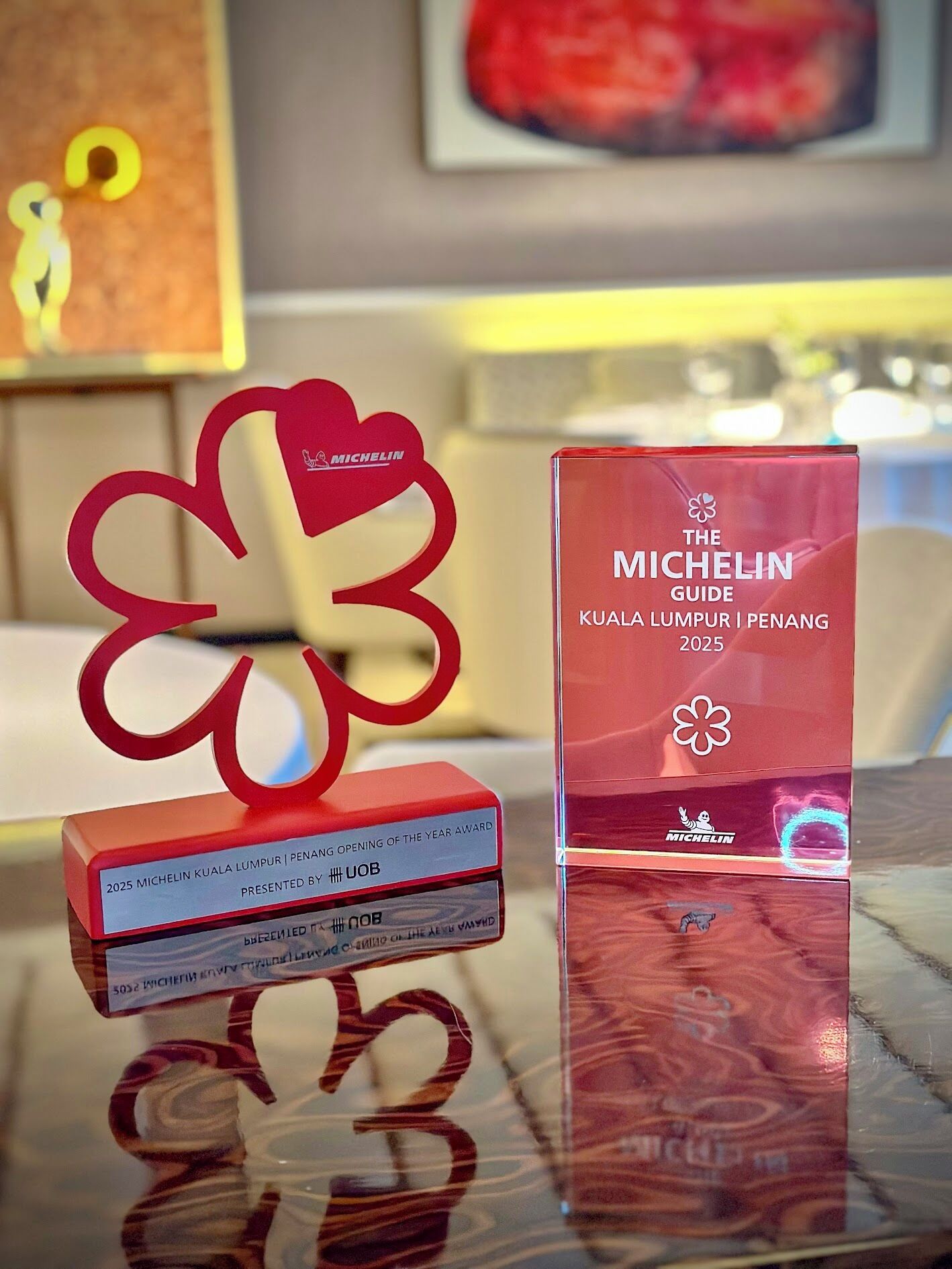 A red award plaque and a clear award box with text on a reflective surface.
