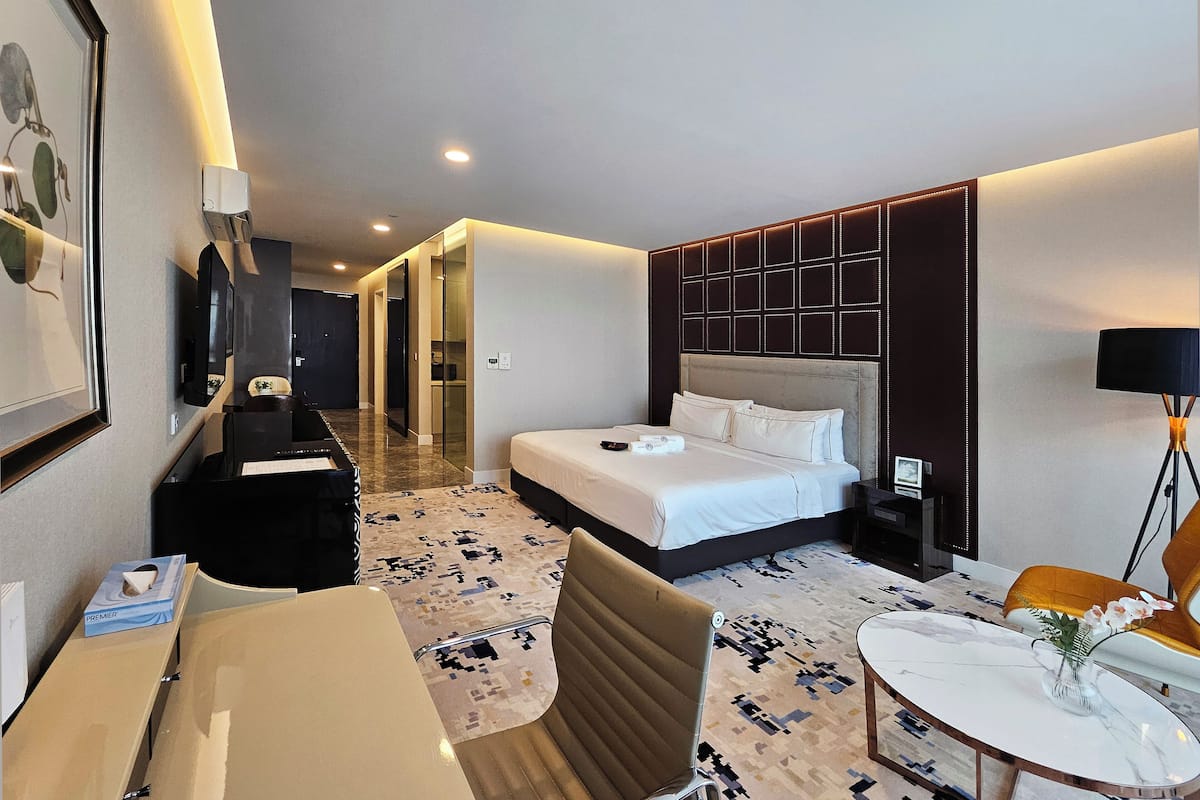 Ein Hotelzimmer mit einem Bett, einem Schreibtisch, einem Stuhl, einem kleinen Tisch mit einer Vase und einer Lampe.