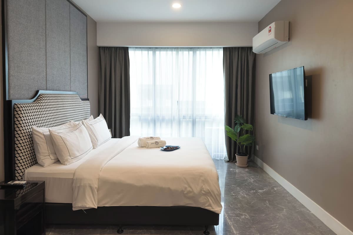 Ein modernes Hotelzimmer mit einem großen Bett, einem flachbildfernseher an der Wand und einer Topfpflanze.