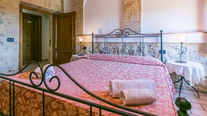 Une chambre à coucher avec un lit, une porte en bois, un mur en pierre et une petite table avec une lampe.