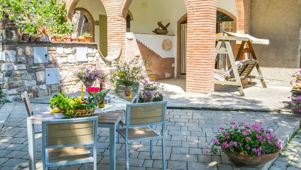 Un espace extérieur aménagé avec une table et des chaises, entouré de plantes et de fleurs en pot.