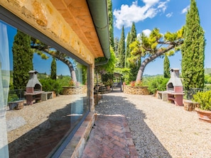 A courtyard with a stone pathway, two outdoor fireplaces, and a pergola with climbing plants.
