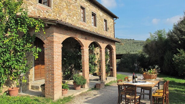 Un edificio rústico de piedra con un patio y zona de estar al aire libre.