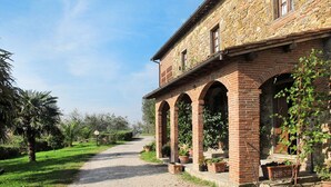 Un edificio de piedra con un camino de grava que conduce a una zona cubierta con arcos.